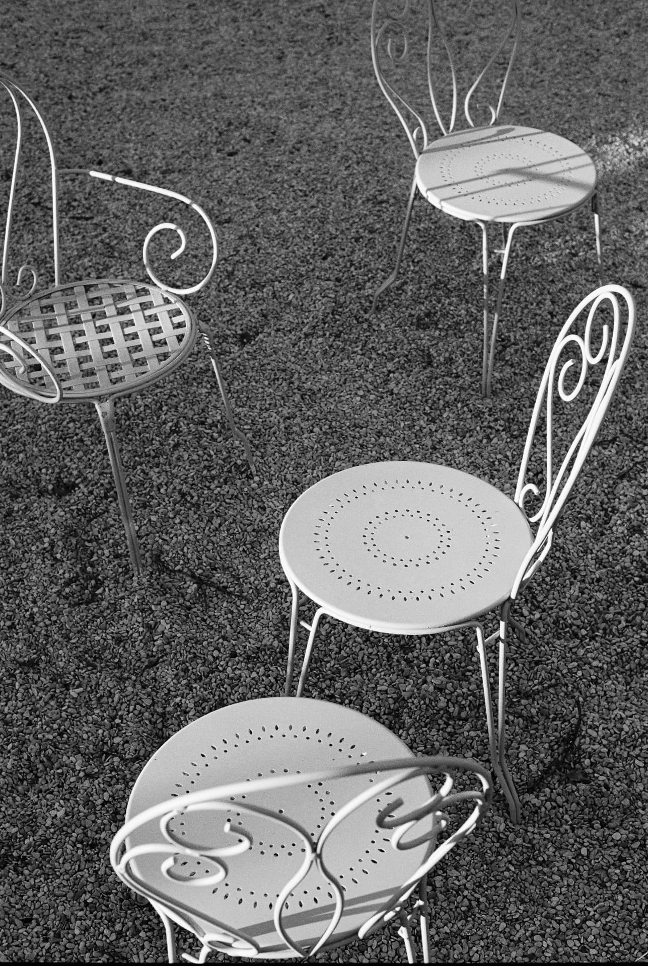 Weiße schmiedeeiserne Gartenstühle in analogem Schwarz-Weiß