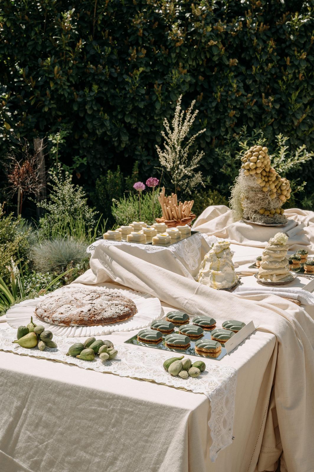 Buffettisch mit Torten, Feingebäck und frischen Feigen vor einer grünen Hecke