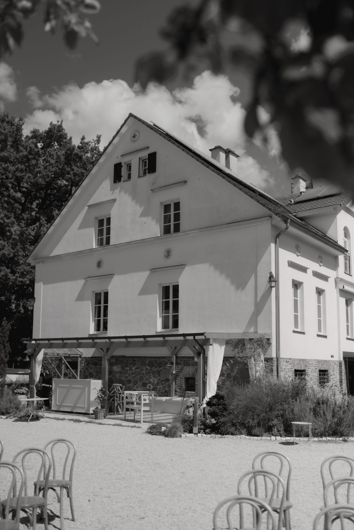 Das weiße Gutshaus der Villa Fuchs mit Stühlen vor der Terrasse