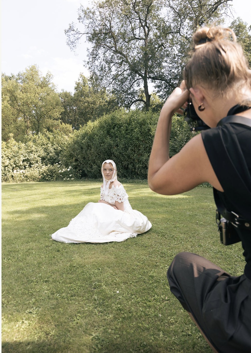 Eine Fotografin fotografiert eine Model Bride auf der Gartenwiese