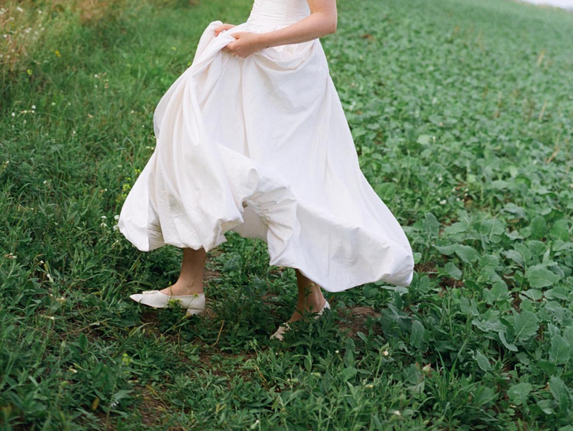 Eine Braut in weißem Kleid, die über ein Feld mit Blattgemüse läuft