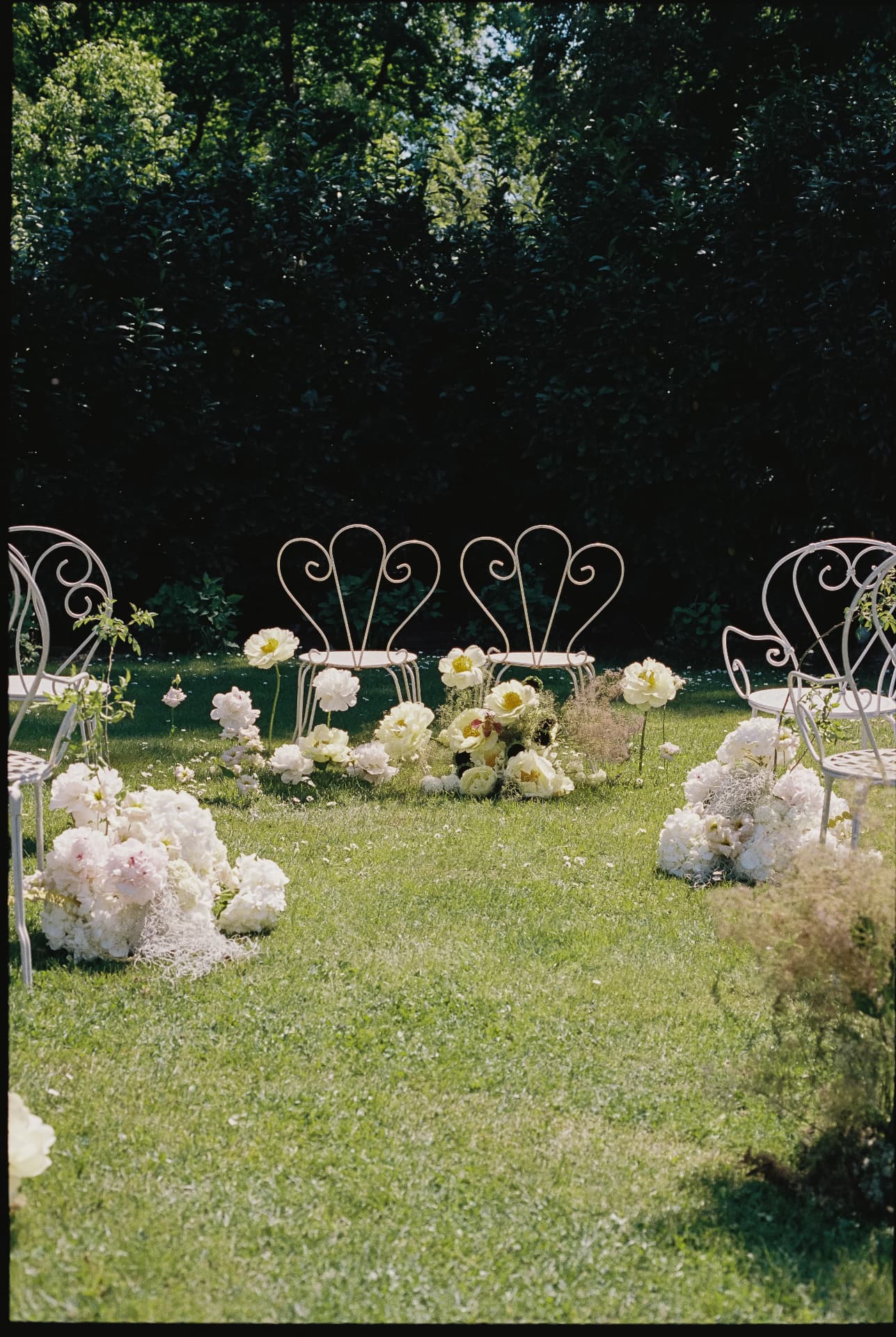 Blumengeschmückte Trauung mit herzförmigen Gartenstühlen
