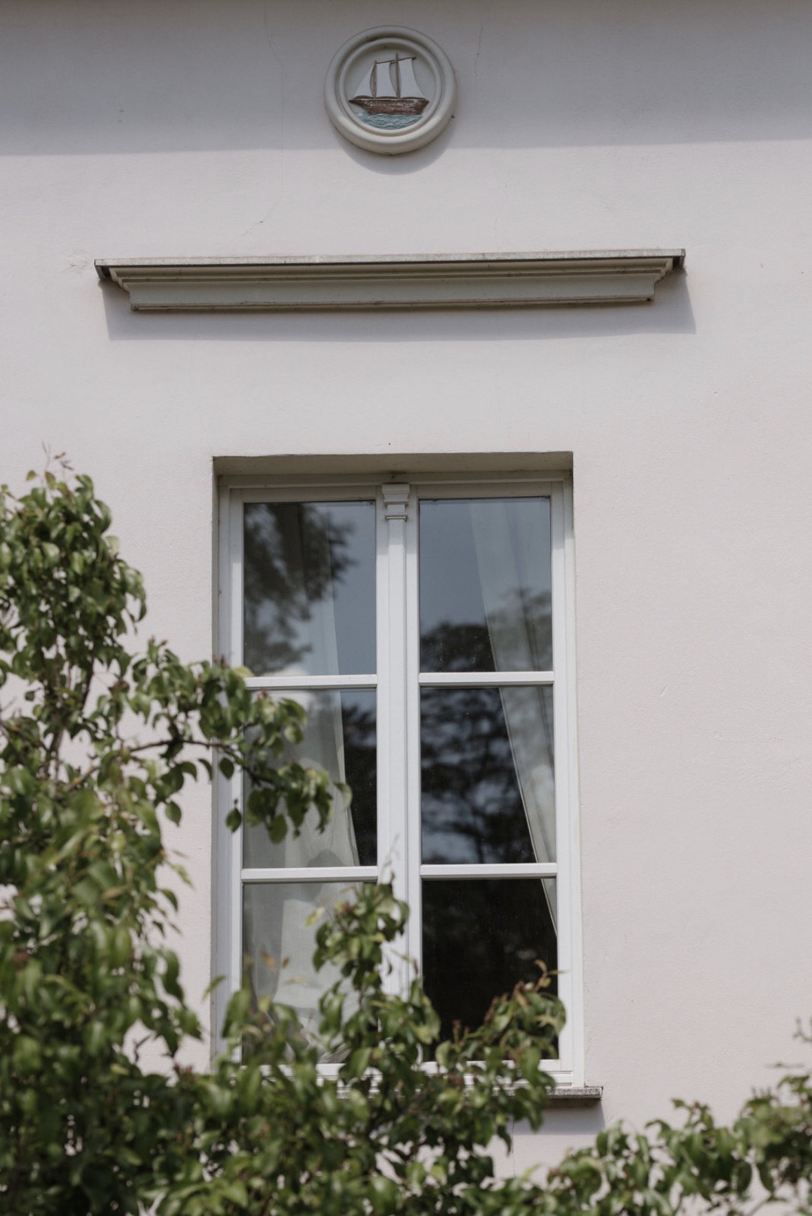 Ein rundes Medaillon mit Schiff über einem Fenster des Hauses