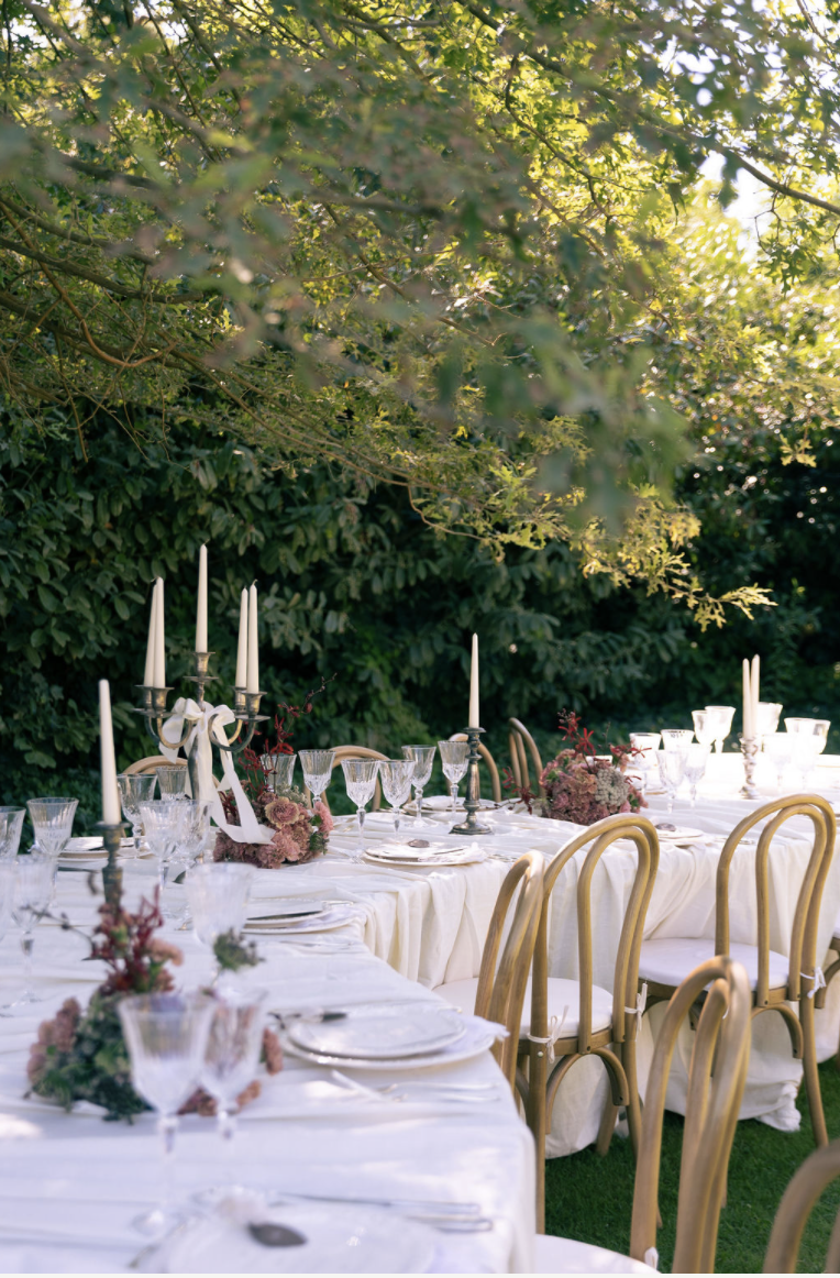 Festliche Gartentafel mit Kerzen, Kristallgläsern und goldenen Stühlen
