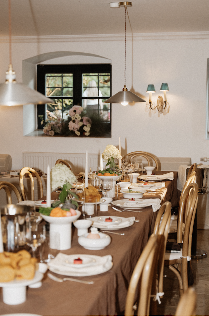 Lange Tafel mit brauner Tischdecke, Blumen und Kerzen in der Weinstube
