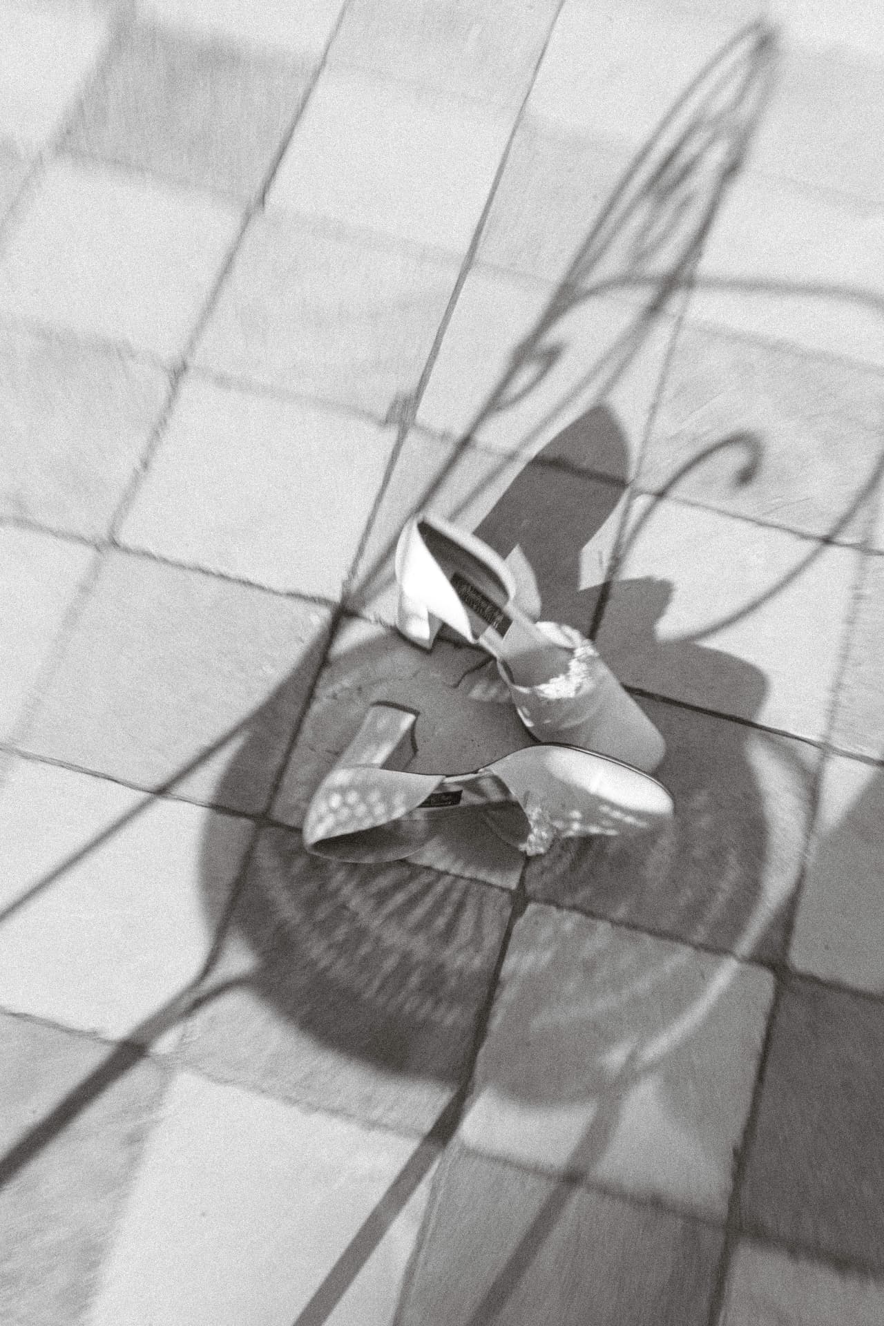Brautschuhe im Sonnenlicht mit grafischen Schatten auf den Steinplatten